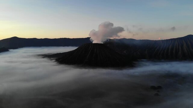Aerial drone flight towards Mount Bromo through fog before sunrise &ndash; Java, Indonesia