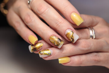 Elegant yellow nails with butterfly designs on fingers in a beauty studio 