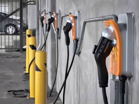 LOS ANGELES, CA, NOV 1, 2025: electric vehicle chargers mounted on a parking garage wall with yellow safety bollards in the foreground