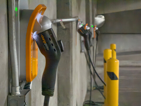 LOS ANGELES, CA, NOV 1, 2025: close-up of ChargePoint electric vehicle chargers glowing green in a dim parking structure with safety bollards visible