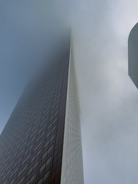 LOS ANGELES, CA, NOV 7, 2025: Two skyscrapers edge-to-edge, one with a bold chevron fa&ccedil;ade, both dissolving into thick white fog above