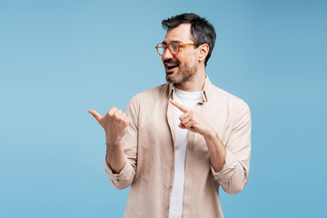 Fototapeta premium Happy man pointing sideways and thumbing back, showing advertisement space