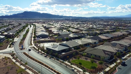 Obraz premium Stunning drone shot of the new Cadence master-planned neighborhood in Henderson. High-angle view of modern streets, intersections, and houses against the Nevada mountains and a cloudy blue sky.