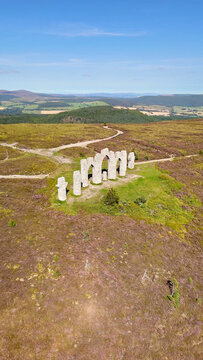 A 18th-century stone Fyrish monument in Scotland under clear blue sky, drone perspective.
