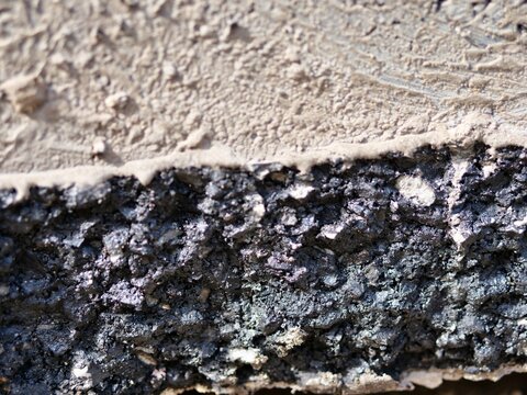 Extreme close-up asphalt and concrete edge, cross-section of road construction materials, 
gritty black bitumen texture, rough grey cement surface, industrial material layers