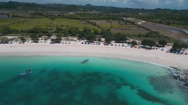 Small Boats Gather By White Sandy Beach. Fishing Boats And Charters Return Over Patterned Seabed. Aerial Perspective Of Vessels And Intricate Seafloor Designs Close To Pristine Beach, Lombok