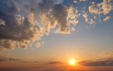 Obraz premium The sky glows with warm colors as the sun sets, with dramatic clouds enhancing the scenic beauty of the evening.