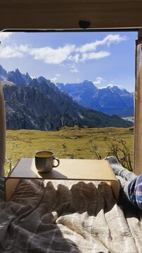 Hands holding two cups of tea with window view of Tre Cime mountains.

Cozy travel moment with warm drinks and epic alpine scenery.