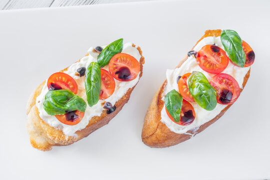 Gourmet bruschetta with stracciatella cherry tomatoes basil and balsamic on bright rustic background