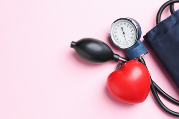Measuring blood pressure. Sphygmomanometer and red heart figure on pink background, top view. Space for text