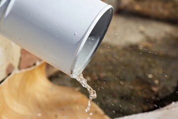 Clear snowmelt cascades from a roof downspout, signifying spring's thaw. Fresh water streams, creating a dynamic splash © PhotoChur