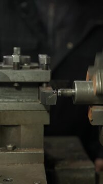 Industrial lathe cuts metal threads on a cylindrical shaft. Metallurgical plant concept.