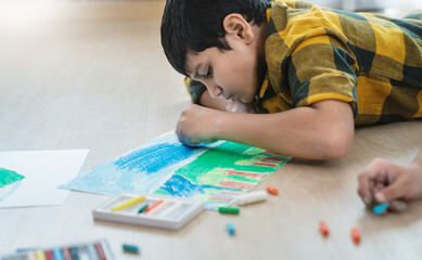 Close up indian arab boy drawing with crayons on the floor during an art activity in a bright classroom setting. Education back to school earth day concept © paulaphoto