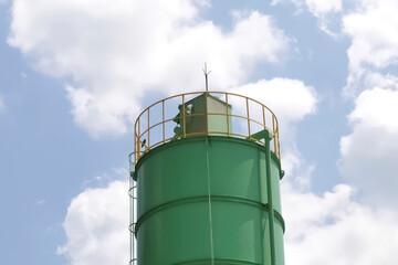 Obraz premium Top of green water tower with equipment and lightning rod
