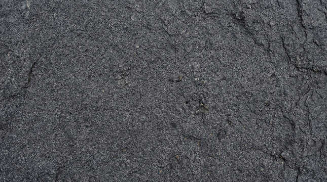 Top view of basalt rock surface with fine crystalline texture and dark grey color, volcanic bedrock concept for geology brand or construction material editorial, no people