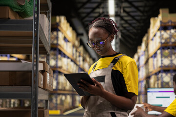 African american female overseeing supply chain process for e-commerce order fulfillment. Shelving...