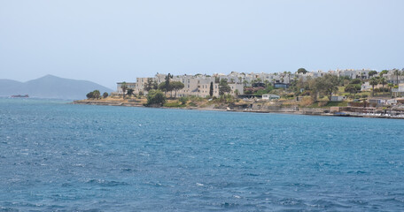 Sunny day by the sea in a coastal town with calm waters and distant mountains