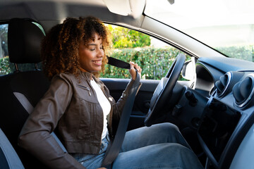 Naklejka premium Happy young woman driving a car and smiling – female driver lifestyle