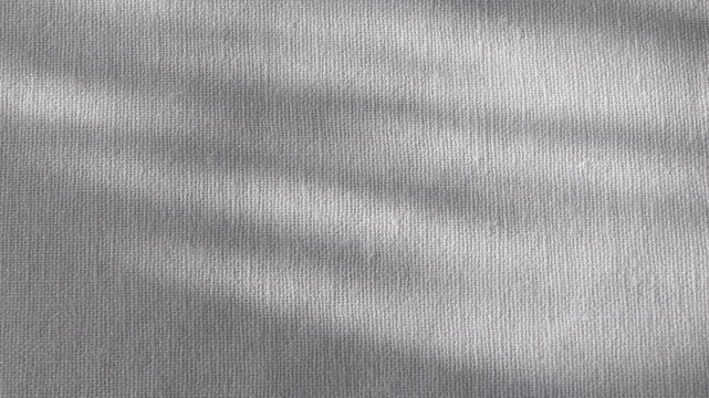 Close-up of rough white linen fabric with sunlight highlights and soft shadows. Minimal textile background with copy space, ideal for natural, organic and lifestyle design.