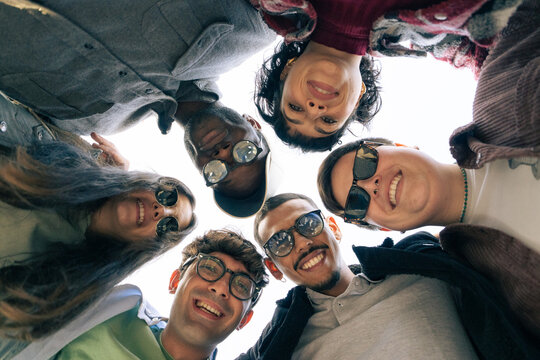 Diverse group of friends looking down at camera forming circle outdoors