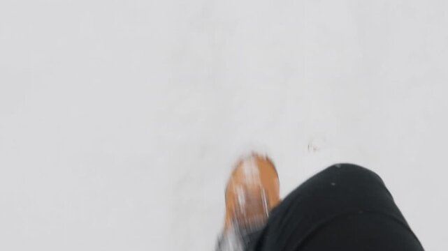 POV shot of person walking through deep snow with boots visible in frame. Slow motion movement shows steps pressing into fresh winter snow creating immersive cold weather scene.