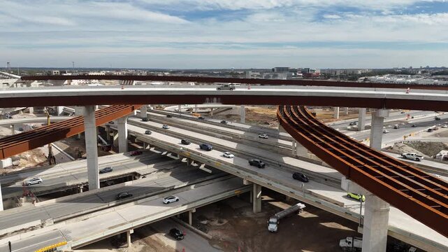 Curved steel bridge girders and elevated ramps under construction at the Interstate 10 and Loop 1604 highway interchange in San Antonio Texas 4k aerial drone video