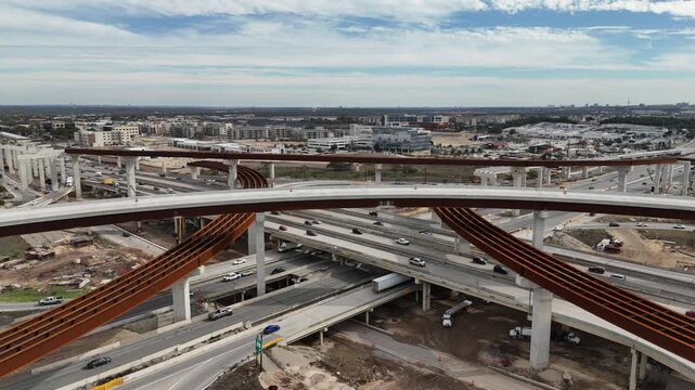 Interstate 10 and Loop 1604 interchange major highway construction project with steel beams and elevated ramps spanning busy traffic in San Antonio Texas 4k aerial drone video