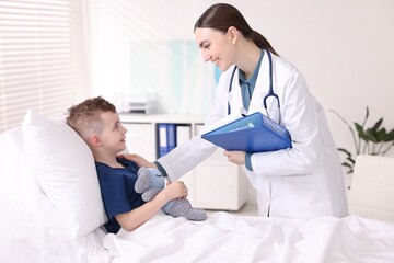 Obraz premium Doctor with folder examining little child in hospital