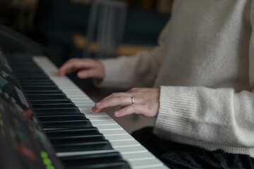 Obraz premium Woman playing piano, close up of hands on piano keys, music practice and creativity