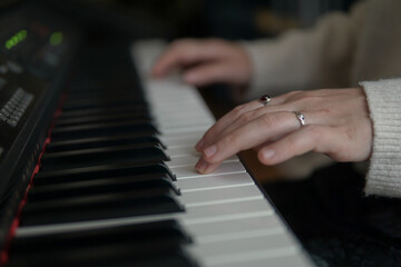 Obraz premium Woman playing piano, close up of hands on piano keys, music practice and creativity