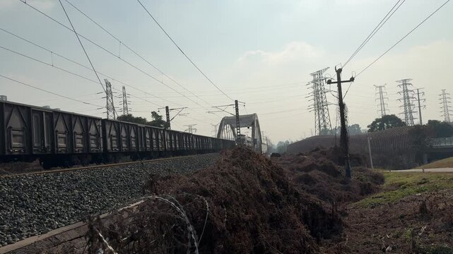 Chengdu, China - March 12 2026: A continuous 4K long shot of a heavy freight train passing over a bridge with authentic rail clatter and locomotive engine sounds.