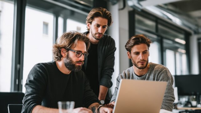 真剣にパソコン画面を見つめる男性たち。チームでの仕事やプロジェクトの打ち合わせに最適なビジネスシーン。