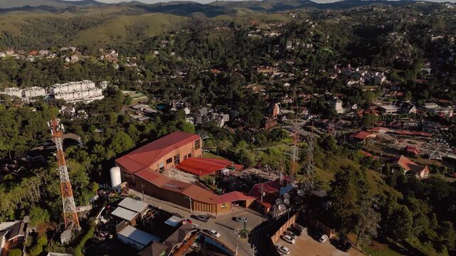 Aerial view of Capivari Park with cable cars, roller coaster, red-roof buildings and surrounding mountain valley cityscape in Campos do Jordao, Brazil. Orbit camera movement