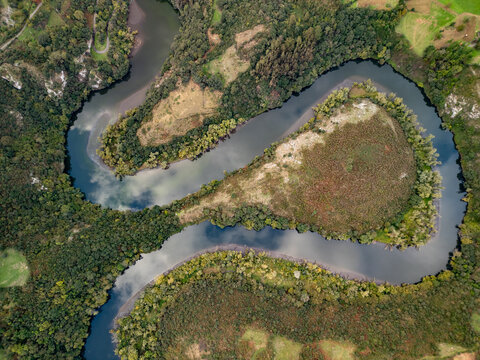 Epic Nora river meander loop top down aerial panorama. 
Cinematic drone view of Asturias canyon water S-curve, 
San Andres reservoir valley and green forest hills near Oviedo Spain.
