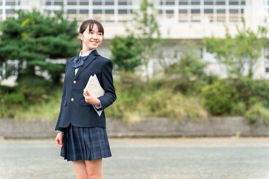 Middle school, high school, and elementary school students in uniform standing in front of the school building.