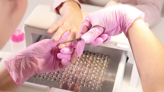 Professional manicurist cutting client's cuticle in beauty salon, closeup