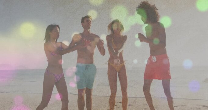 Clapping group of four adults dancing on sandy beach, wearing swimsuits with colorful bokeh overlay