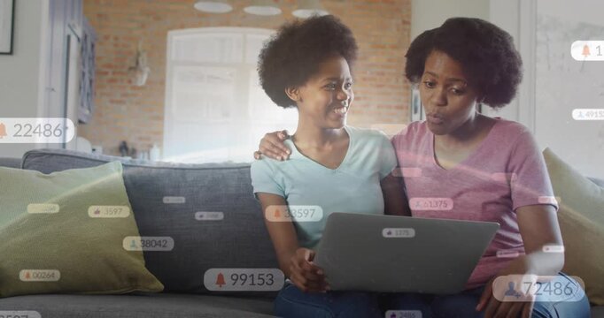 Mother and daughter watching laptop on couch, seeing social badges drifting, celebrating followers