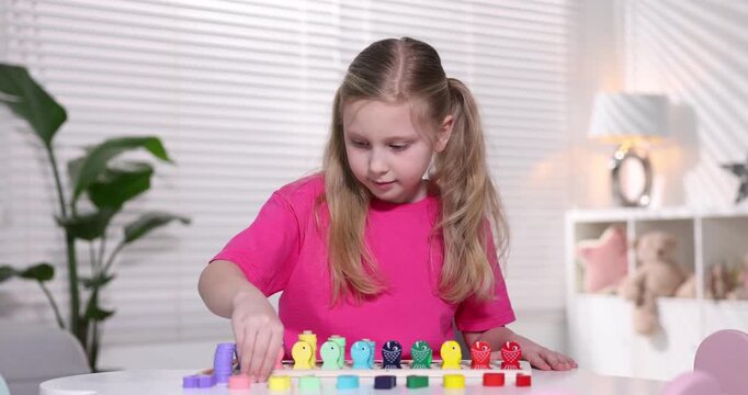 Little girl playing with educational toy at table indoors