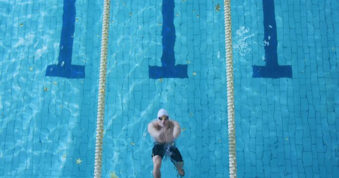 Vertical video: Pushing off block, swimmer in trunks swimming down lane stirring stars for training