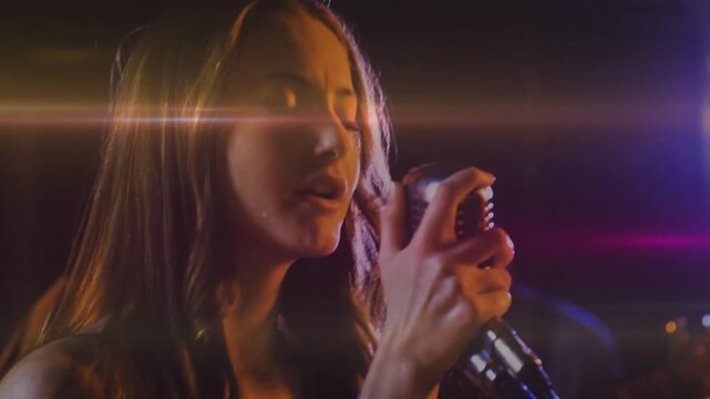 Female singer bringing vintage mic to mouth singing music as lens flares sweeping across face