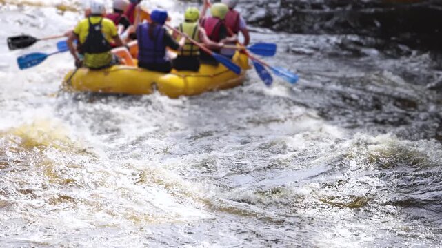 Rafting in whitewater, extreme water sports on water rapids, kayaking and canoeing tour in a mountain river,  water sports team, red and yellow raft boat full of tourists in a summer day, slow motion