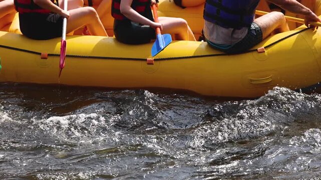 Rafting in whitewater, extreme water sports on water rapids, kayaking and canoeing tour in a mountain river,  water sports team, red and yellow raft boat full of tourists in a summer day, slow motion
