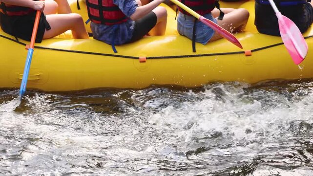 Rafting in whitewater, extreme water sports on water rapids, kayaking and canoeing tour in a mountain river,  water sports team, red and yellow raft boat full of tourists in a summer day, slow motion