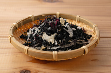 Dried mixed seaweed salad in a bamboo basket on a wooden table