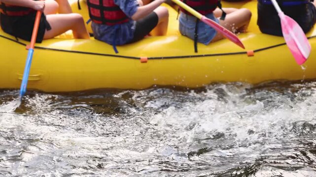 Rafting in whitewater, extreme water sports on water rapids, kayaking and canoeing tour in a mountain river,  water sports team, red and yellow raft boat full of tourists in a summer day, slow motion