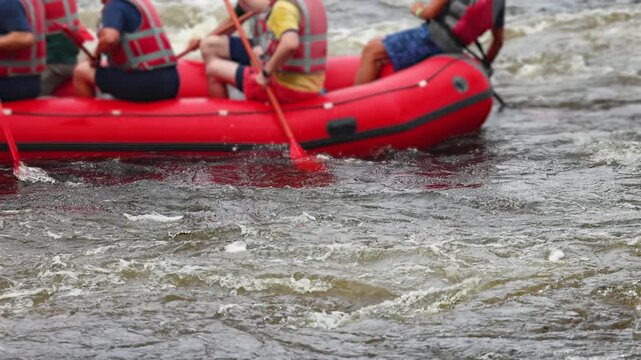 Rafting in whitewater, extreme water sports on water rapids, kayaking and canoeing tour in a mountain river,  water sports team, red and yellow raft boat full of tourists in a summer day, slow motion