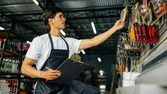 Man in apron organizing products and checking stock in a hardware shop
