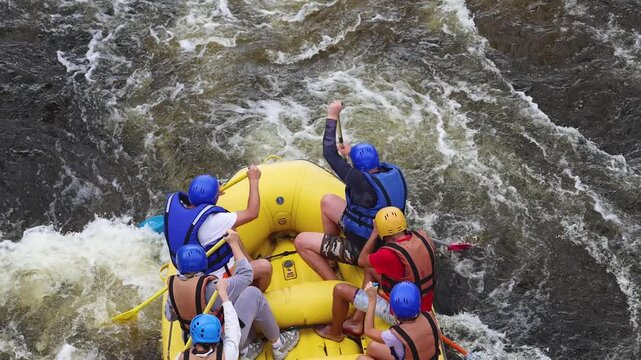Rafting in whitewater, extreme water sports on water rapids, kayaking and canoeing tour in a mountain river,  water sports team, red and yellow raft boat full of tourists in a summer day, slow motion