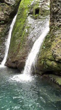 Stunning 4K 120fps vertical scene of twin waterfalls pouring into a turquoise pool, featuring mossy cliffs and soothing water sounds.